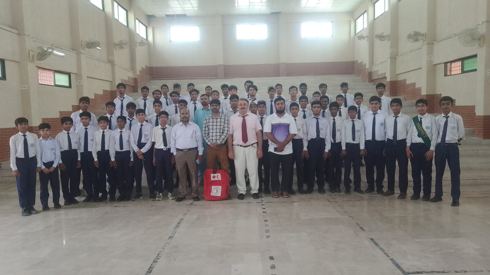 Several school children seated on the floor in a room, participating in a group learning first Aid session.