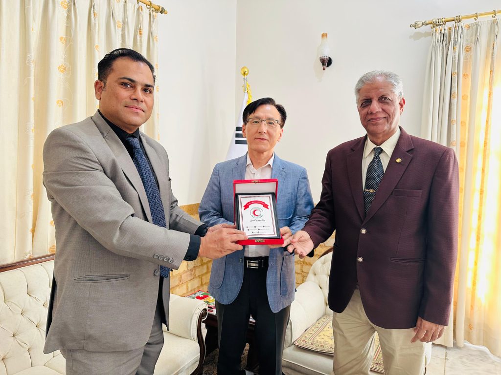 A room with three men sitting on a white couch, appearing engaged in discussion
