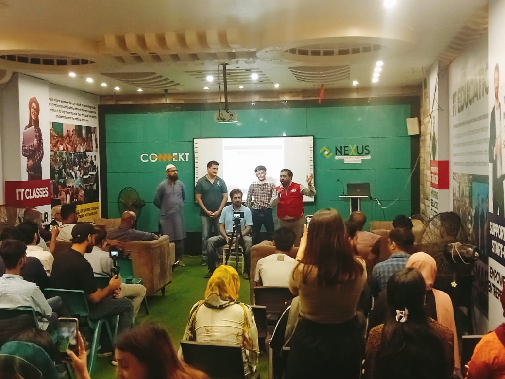 A man in a red Jacket stands in front of a screen, presenting first aid techniques at RJ Mall's orientation session