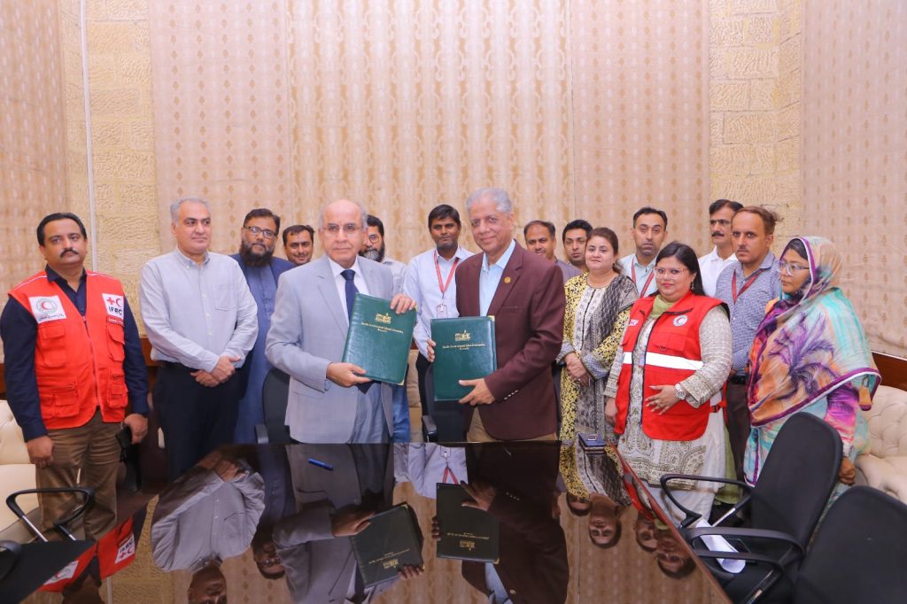 Two men shake hands at a table, finalizing a Memorandum of Understanding for climate action and community resilience