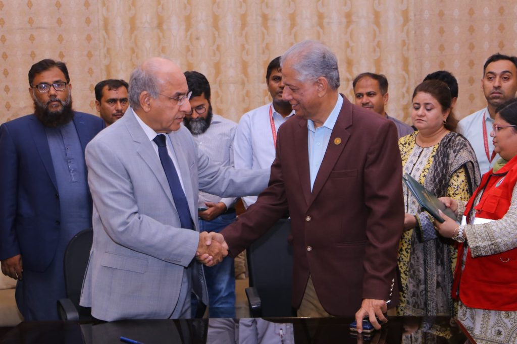Two men shake hands at a table, finalizing a Memorandum of Understanding for climate action and community resilience