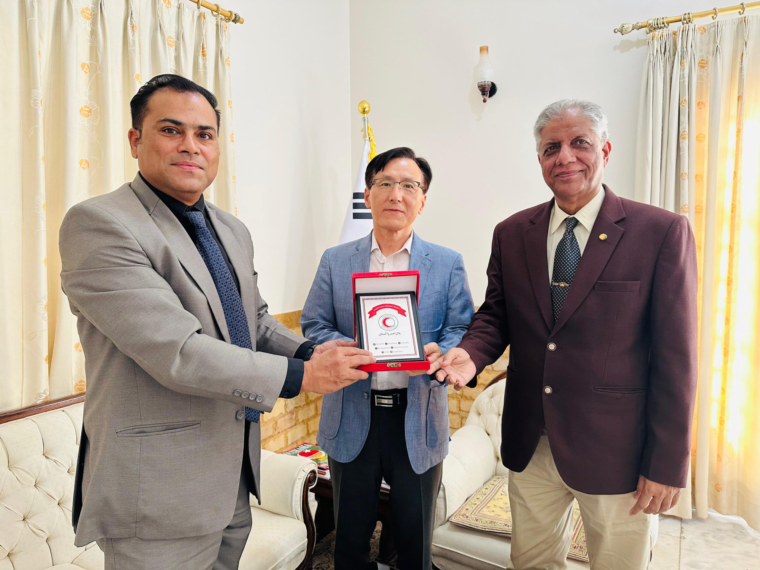 A room with three men sitting on a white couch, appearing engaged in discussion