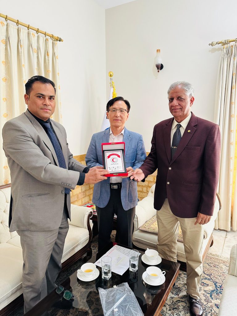 A room with three men sitting on a white couch, appearing engaged in discussion