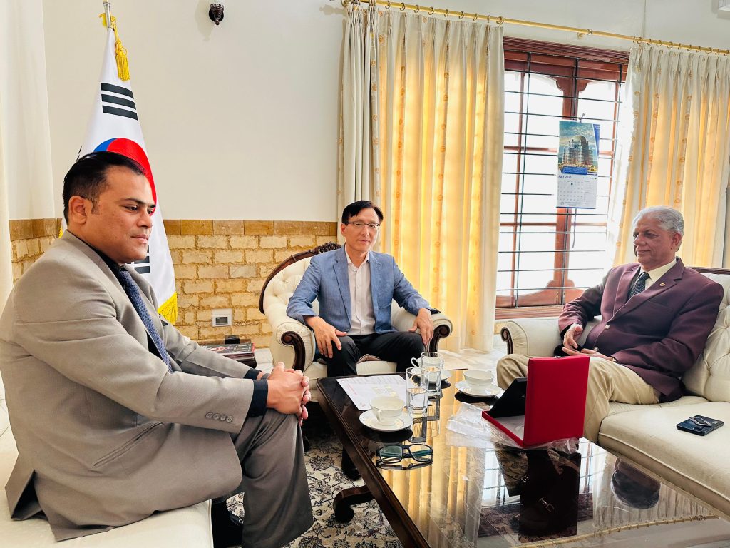 A room with three men sitting on a white couch, appearing engaged in discussion