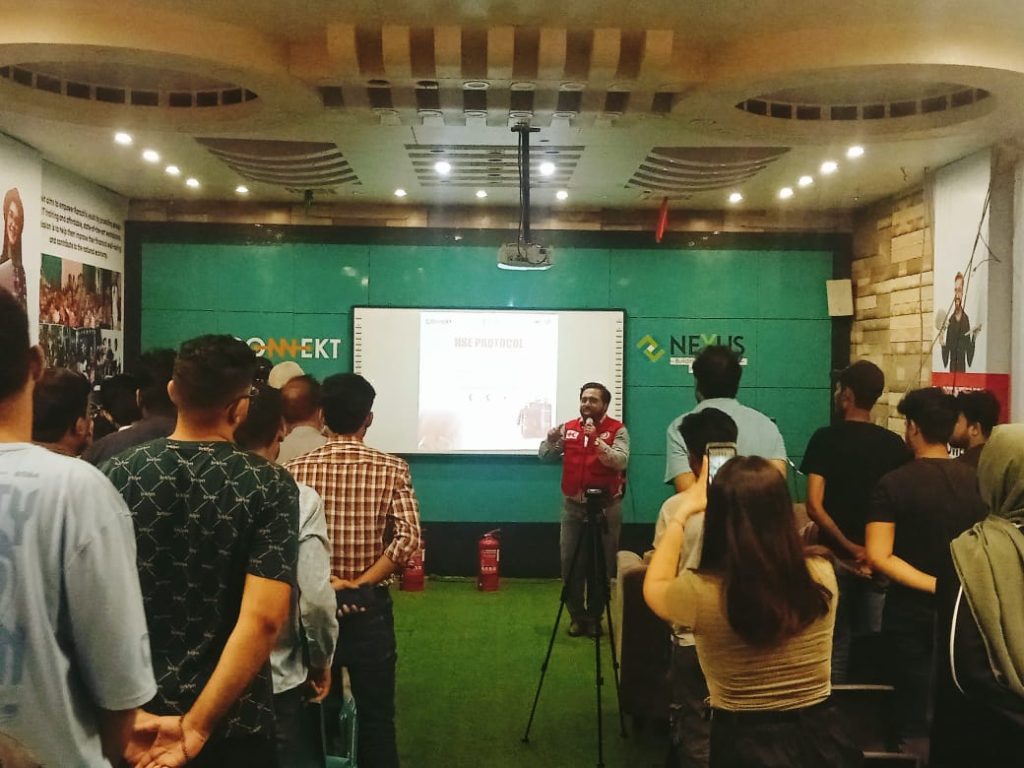 A man in a red Jacket stands in front of a screen, presenting first aid techniques at RJ Mall's orientation session